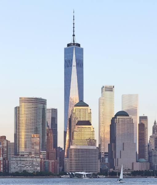 Blick auf New York City mit dem One World Trade Center und weiteren Hochhäusern am Wasser, moderne Glasfassaden und klare Stimmung.