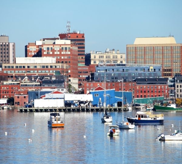 Portland Hafenpanorama in Maine: ruhiges blaues Wasser, Bootsbewohner vor roten Backsteingebäuden, farbenfrohe Hafenhäuser und Bootskutter am Kai