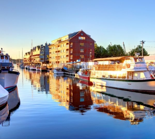 Hafen in Portland, Maine mit mehreren Booten, reflektierenden Wassern, historischen Gebäuden am Ufer und warmem Sonnenlicht, Portland-Blick