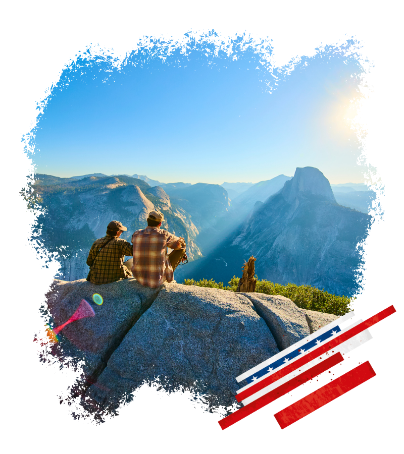 Zwei Wanderer genießen den Blick auf eine weite Berglandschaft beim Sonnenaufgang; dazu eine USA-Flagge im Vordergrund und Fernblicke bis zum Horizont.