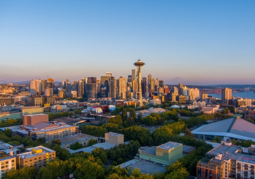Seattle im warmen Abendlicht mit der Space Needle über der Skyline des Pazifischen Nordwestens und Blick auf die Bucht im Hintergrund.