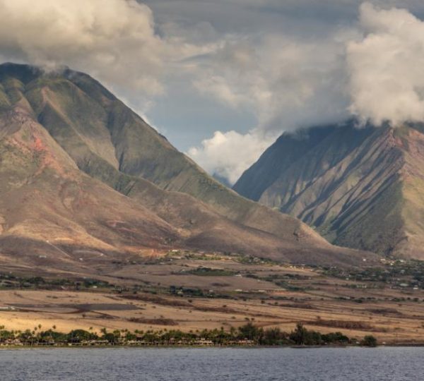 Blick auf die trockene Berglandschaft von Lahaina auf Maui mit grünen Hängen, Feldern und blauem Küstenwasser
