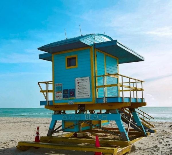 Bunte Rettungsschwimmerstation am Strand von Miami Beach mit türkisblauem Meer und gelb-blauem Wachturm in Florida
