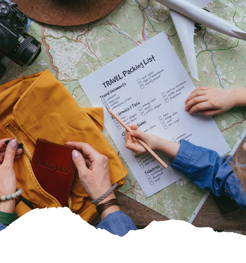 Reisepass, USA-Karte, Packliste und Kamera liegen auf einer Landkarte, während Hände Kleidung und Reisepapiere für die Abreise sorgfältig sortieren.