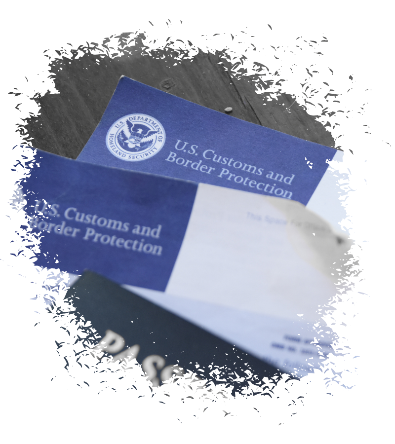 Im Vordergrund liegen blaue und weiße US-Einreiseunterlagen mit dem Schriftzug U.S. Customs and Border Protection und DHS-Emblem.