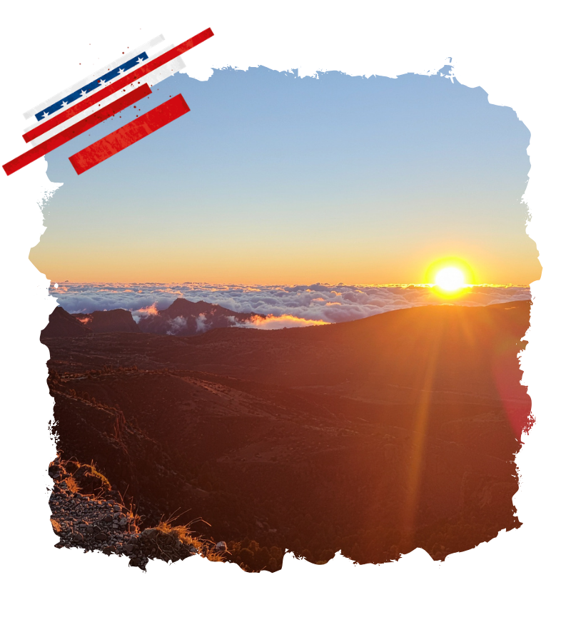 In goldenem Licht geht die Sonne über dem Haleakala Nationalpark auf und taucht die Vulkanlandschaft samt Wolkendecke in warme Farben.