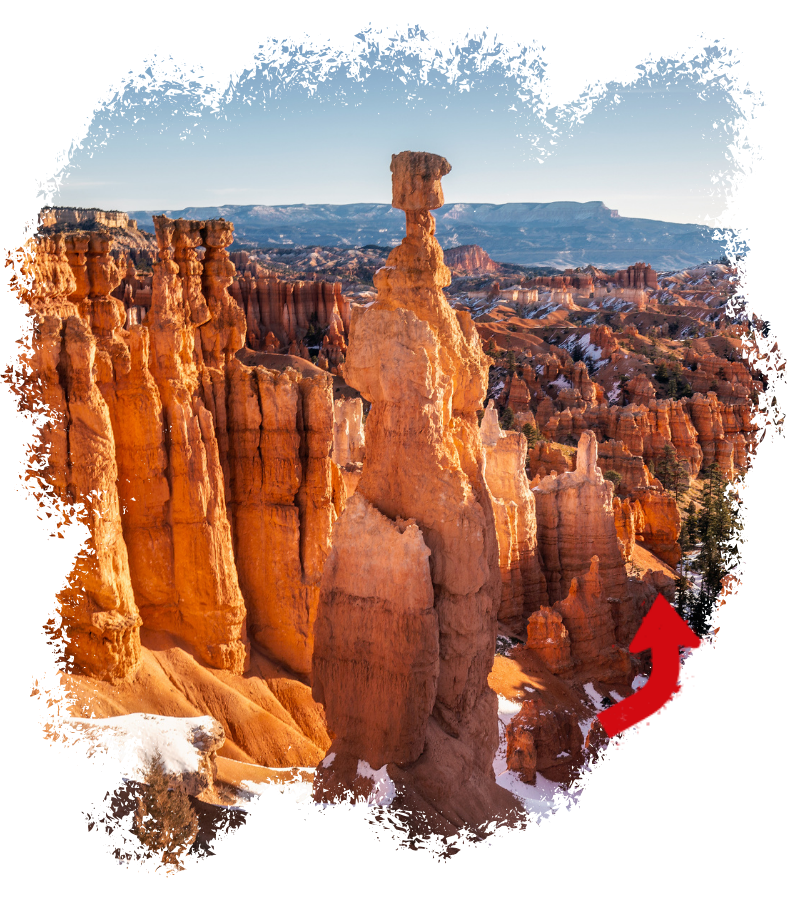 Im Bryce Canyon ragen orangefarbene Hoodoos und ein markanter Felsturm über verschneite Hänge, während im Hintergrund weite Plateaus liegen.
