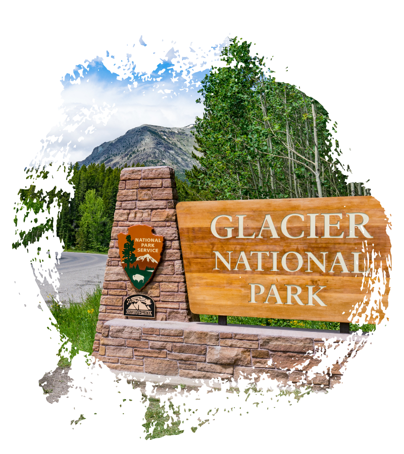 Holz- und Steinschild am Glacier National Park vor bewaldeten Bergen und einer kurvigen Straße an einem klaren Tag im Sommer.