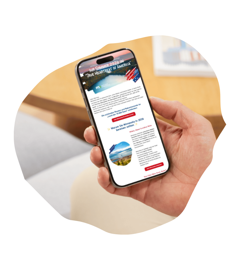 Eine Hand hält ein Smartphone mit dem USA-Reisen-Experte-Newsletter und Reiseinhalten zu Minnesota, Amerika und Sommerreise-Ideen.