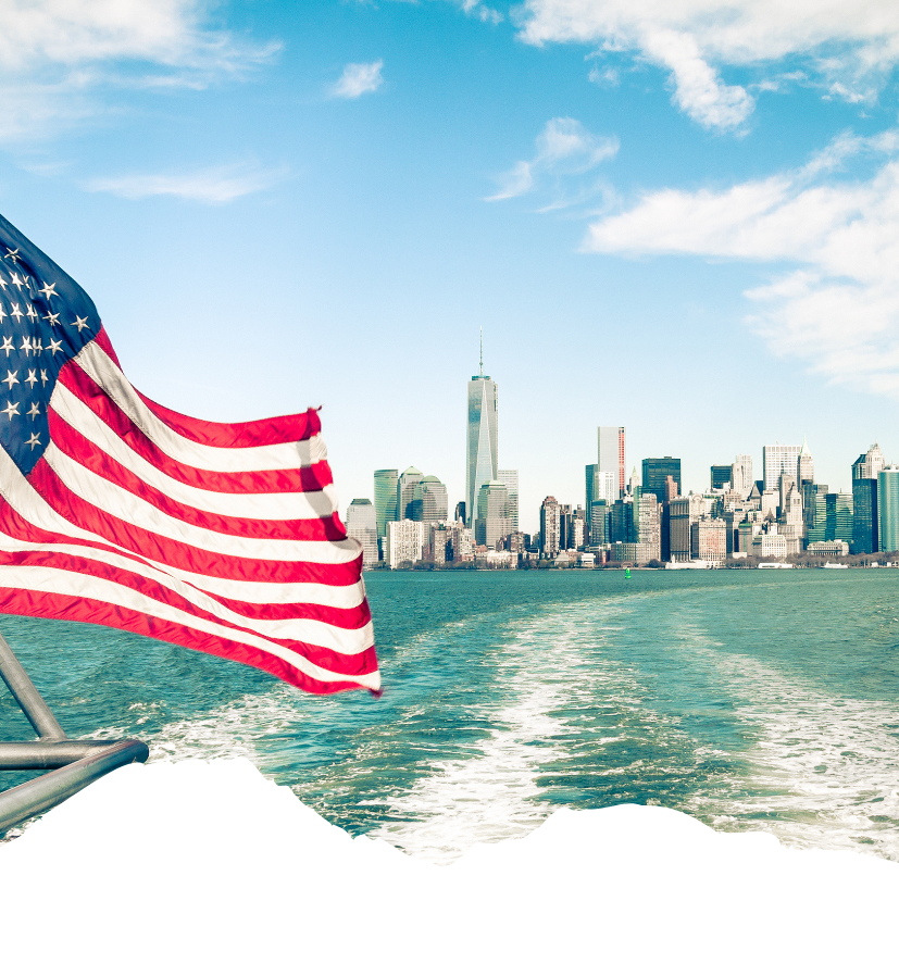 Vor der Skyline von Lower Manhattan weht die US-Flagge, während das Boot eine Spur auf dem Wasser zieht und den Blick auf New York City öffnet.