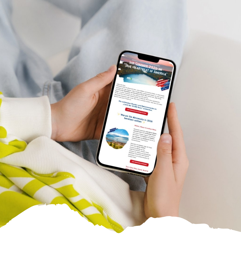 In den Händen einer Person ist ein Smartphone zu sehen, auf dem ein USA-Newsletter mit Minnesota, Sommer 2026 und Reisetipps geöffnet ist.