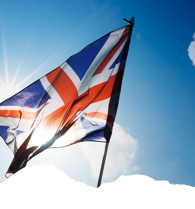 Die britische Flagge weht vor blauem Himmel und hellem Sonnenlicht, während die UK-ETA-Pflicht für Reisen über Großbritannien im Fokus steht.