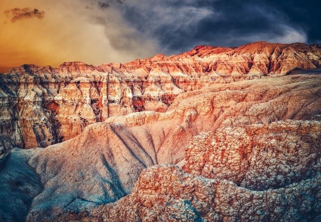 Rote Felsformationen im Yellowstone-Nationalpark leuchten unter einem dunklen Himmel in warmem Abendlicht.