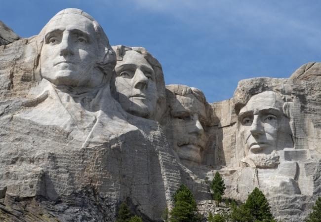 Die Granitgesichter von Mount Rushmore ragen vor blauem Himmel empor und prägen die Felswand in South Dakota.