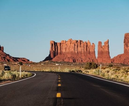 Eine geschwungene Straße führt durch die Wüstenlandschaft mit roten Felsformationen entlang der Route 66.