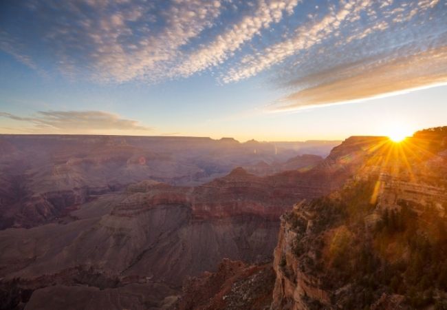 Die Sonne geht über dem Grand Canyon im Südwesten Arizonas auf und taucht die roten Canyonkanten in warmes Licht.
