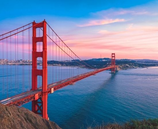 Die Golden Gate Bridge spannt sich rot über die Bucht von San Francisco, während der Himmel in Rosa und Blau leuchtet.