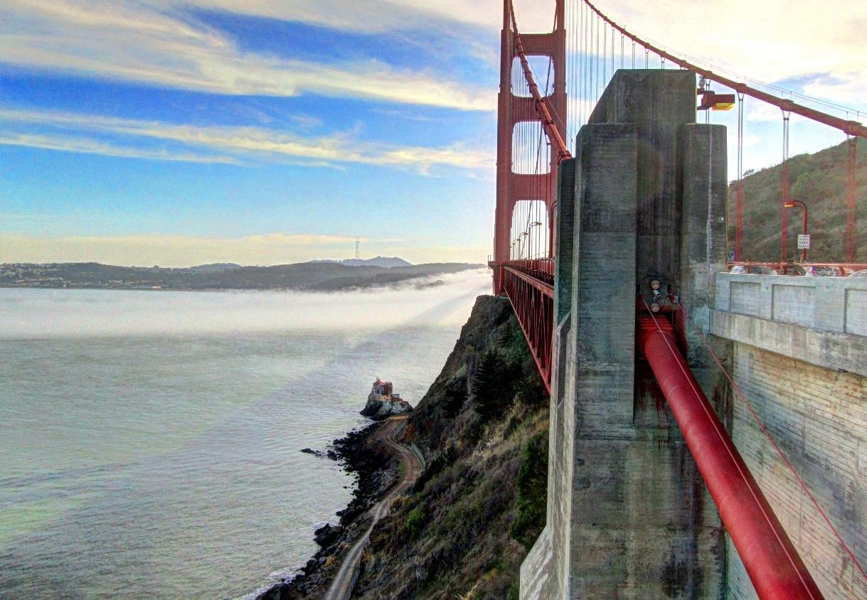 Die Golden Gate Bridge ragt über der Bucht von San Francisco, während tiefer Nebel die Küste und das Wasser bedeckt.