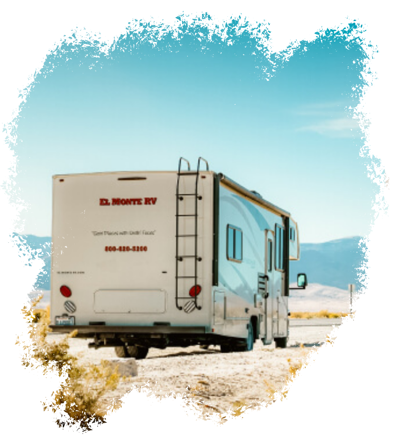Ein blaues El Monte RV steht auf hellem Wüstenboden vor niedrigen Bergen unter klarem, weitem Himmel.