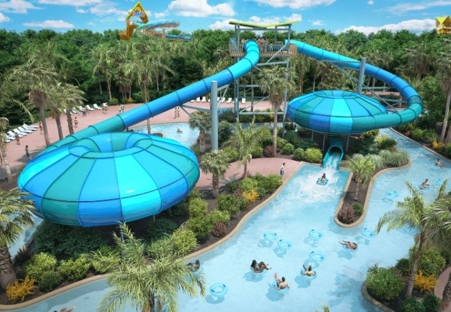 Im Aquatica in Orlando schlängeln sich blaue Wasserrutschen über eine tropische Anlage mit Lagune, Palmen und Badegästen.