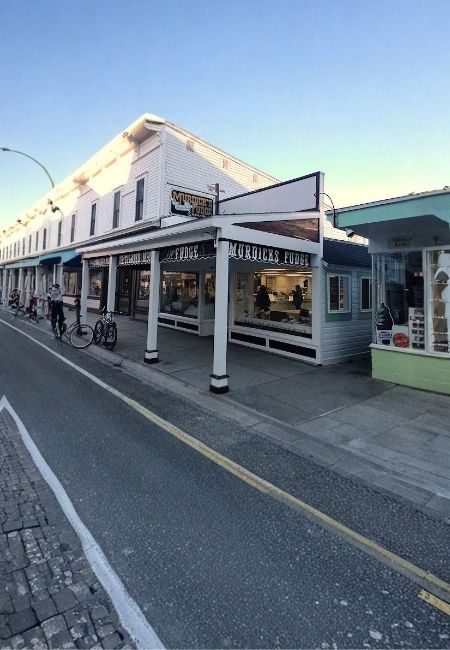Vor dem Laden Murdick's Fudge auf Mackinac Island stehen Fahrräder an der Straße bei Abendlicht.