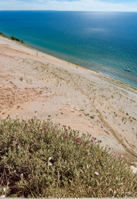 Über steile sandige Dünen von Sleeping Bear Dunes blickt man auf das türkisblaue Wasser der Great Lakes.