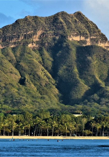 Diamond Head erhebt sich über Oʻahu, davor liegen Palmenstrand und ruhiges Wasser nahe Waikīkī.