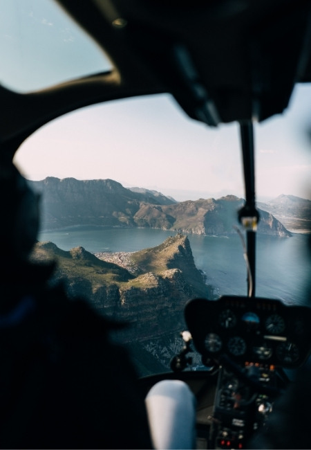 Aus dem Helikopter zeigt sich die zerklüftete Nā Pali Coast mit tiefblauem Wasser und steilen Felsformationen in Hawaii.