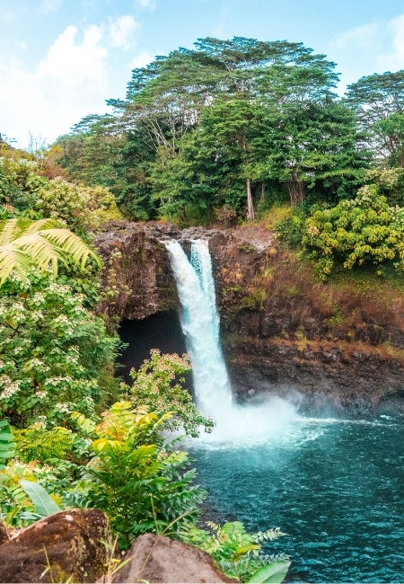 Der Rainbow Falls in Hilo stürzt vor dichtem tropischem Grün in ein türkisfarbenes Becken auf Hawaii.
