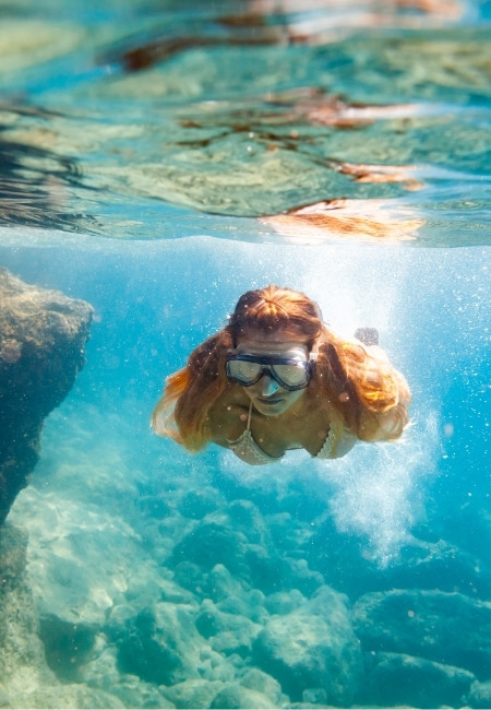 Eine Frau schnorchelt in der Hanauma Bay über einem klaren Korallenriff im türkisblauen Wasser.