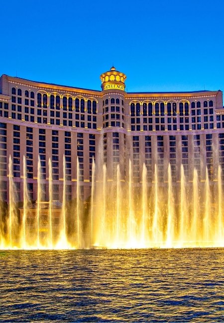 Vor dem Bellagio in Las Vegas steigen goldene Wasserfontänen vor der beleuchteten Fassade bis in den Abendhimmel auf.