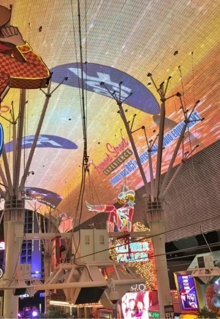 Unter der bunten LED-Decke der Fremont Street in Las Vegas leuchten Neonanzeigen, Schilder und ein auffälliges Cowboy-Motiv über der Fußgängerzone.