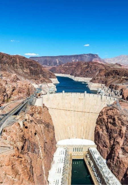 Der Hoover Dam im Black Canyon staut den Colorado River, während sich hinter der Staumauer das blaue Wasser des Lake Mead durch Felsen zieht.