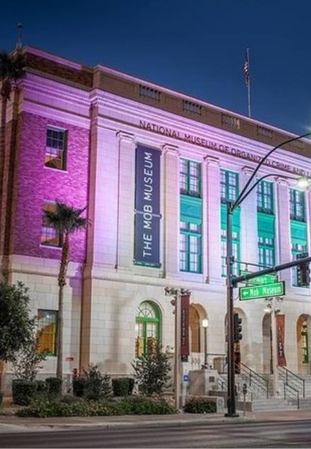 Die beleuchtete Fassade des The Mob Museum in Las Vegas zeigt abends violette und türkisfarbene Akzente an der Straßenecke.