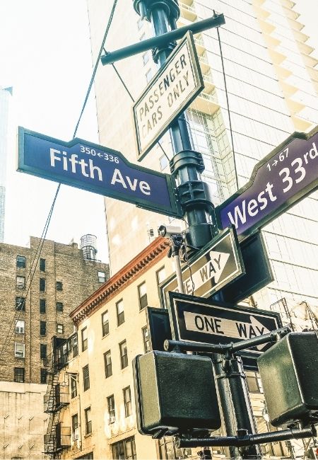 Am Straßeneck in Manhattan zeigen Schilder Fifth Ave und West 33rd Street, dazu stehen One-Way-Hinweise an hohen Gebäuden.