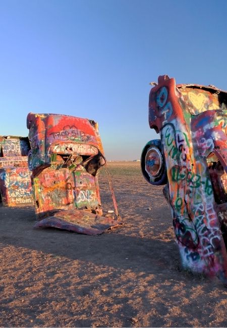 Bunt besprühte Autowracks ragen auf der Cadillac Ranch in der trockenen Landschaft entlang der Route 66 aus dem Boden.