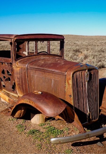 Ein verrosteter Oldtimer steht in der kargen Landschaft des Standin' on the Corner Park an der Route 66.