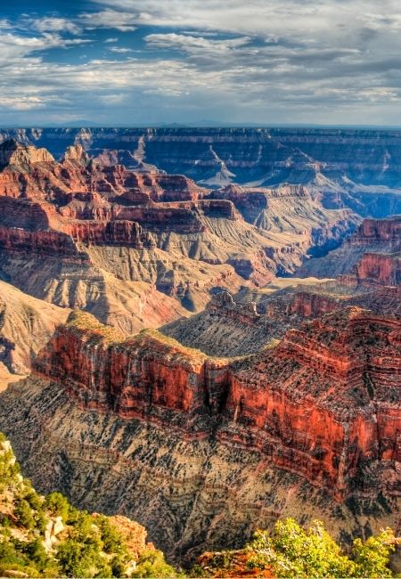 Weitblick über die farbigen Felsstufen des Grand Canyon unter einem wolkigen Himmel in Arizona.