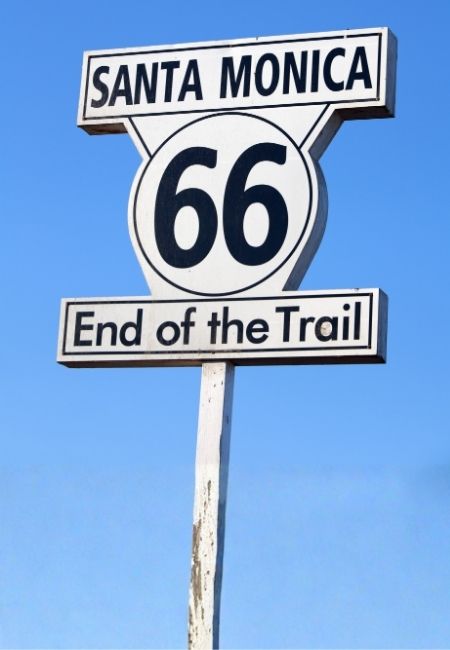 Das Schild in Santa Monica zeigt die Route 66 mit der Aufschrift „End of the Trail“ vor blauem Himmel.