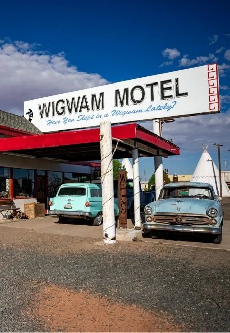 Vor dem Wigwam Motel in Holbrook stehen zwei Oldtimer, daneben ist ein Tipi-Zelt unter dem Route-66-Schild zu sehen.