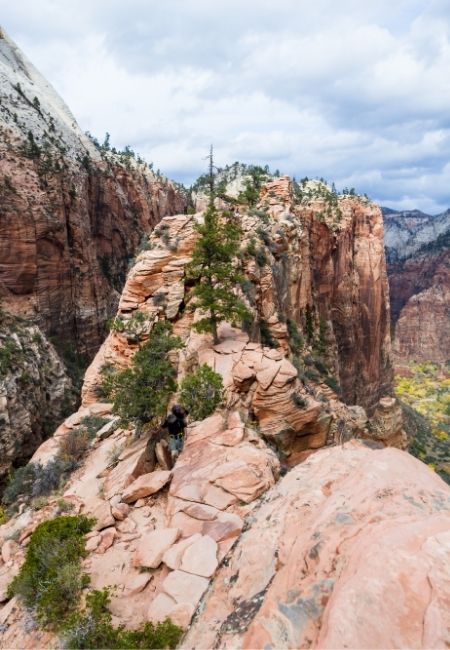 Ein Wanderer steigt auf dem schmalen Grat von Angels Landing im Zion-Nationalpark über roten Felsen.