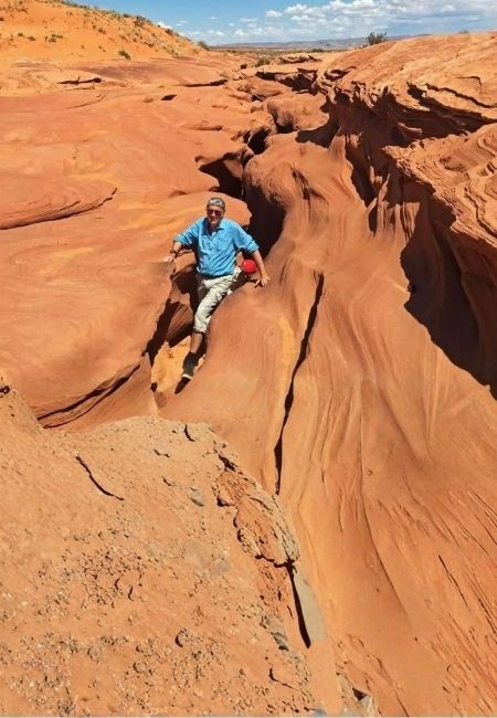 Ein Wanderer steigt durch die rot geschwungenen Sandsteinwände des Antelope Canyon in der Wüste Arizonas.