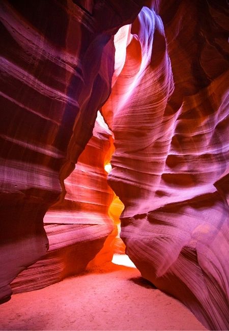 Im Antelope Canyon ragen wellige rote Sandsteinwände eng auf, während warmes Licht den schmalen Durchgang beleuchtet.