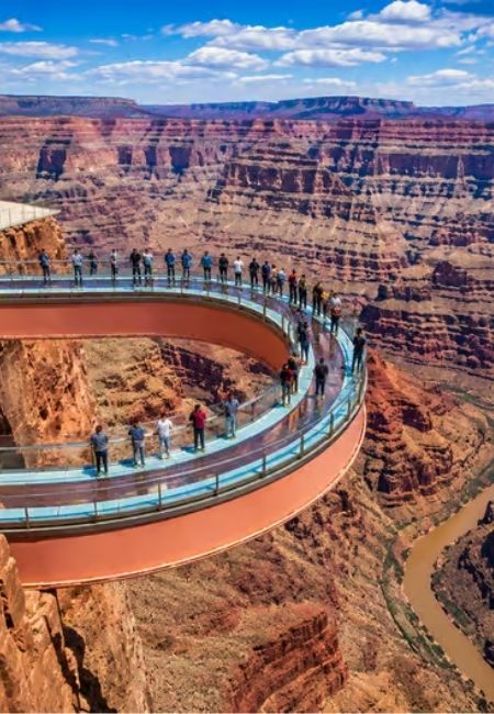 Besucher stehen auf dem Grand Canyon Skywalk und blicken über die tiefen, rotbraunen Felswände des Canyons.