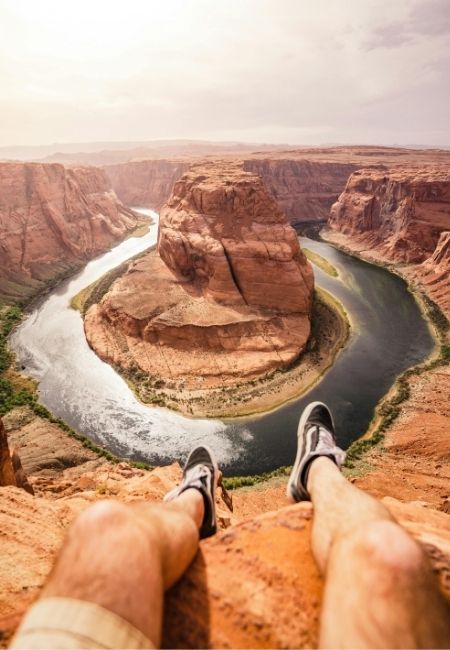 Am Felsrand über dem Horseshoe Bend zieht sich der Colorado River in einer weiten Schleife durch rote Canyons.