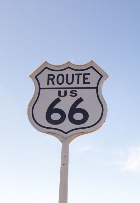Das Route-66-Schild ragt vor einem klaren, hellblauen Himmel auf und verweist auf den berühmten Highway im Südwesten der USA.