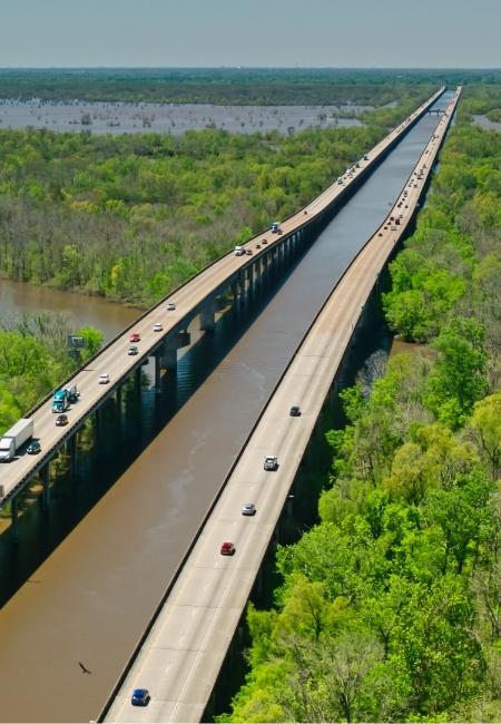 Über dem Atchafalaya Basin in Louisiana führen zwei lange Dammbrücken durch grüne Sümpfe und Wasser.