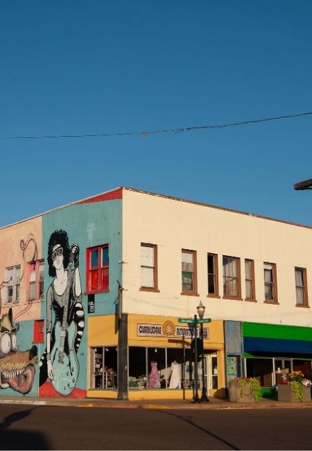 Ein bunt bemaltes Eckgebäude in Clarksdale, Mississippi zeigt ein Musik-Mural mit Gitarristin und Figuren.
