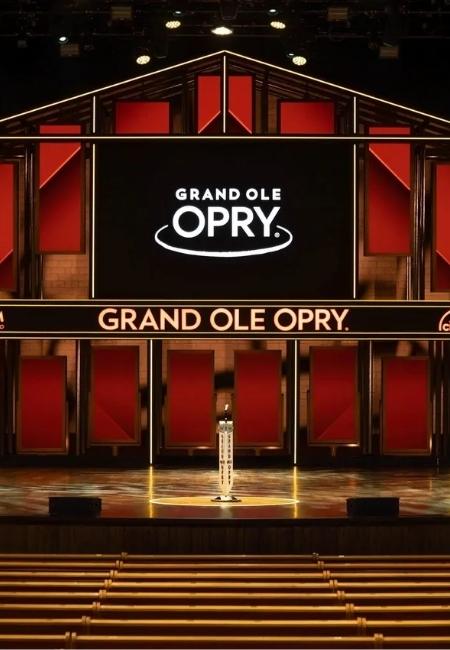 Die Bühne der Grand Ole Opry leuchtet in Rot und Gold, darüber steht der Schriftzug Grand Ole Opry vor leeren Sitzreihen.