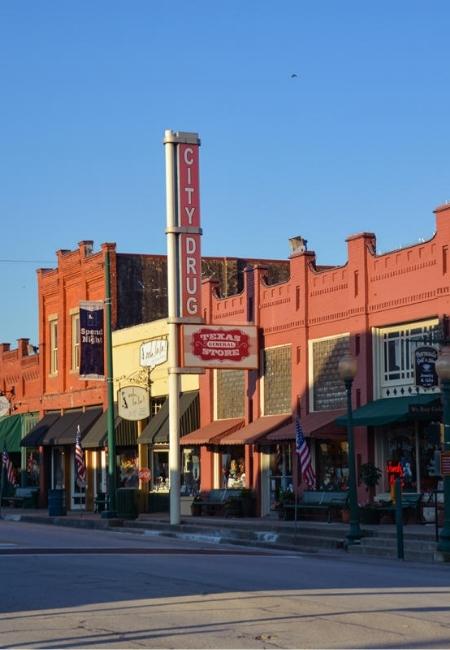 Historische Backsteinfassaden an einer Straße in Grapevine, Texas, mit dem vertikalen City-Drug-Schild.
